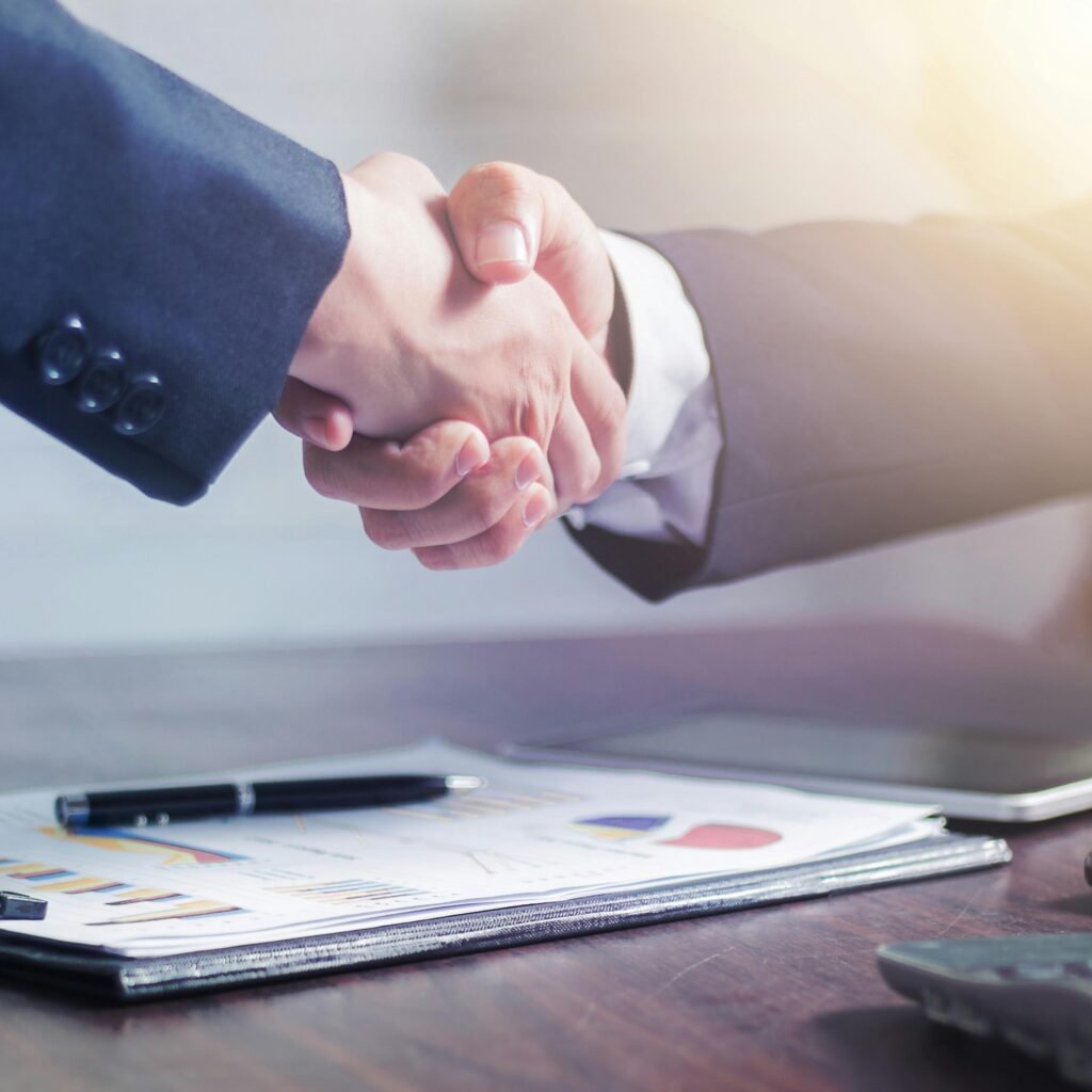 Professional handshake agreement over business charts in an office setting.